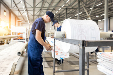 Fototapeta premium Workers in a factory carry out technological processes on a conveyor line in protective overalls