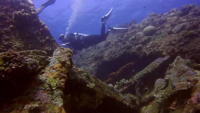 Scuba divers swimming into a shipwreck from the top