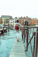 Fototapeta na wymiar woman walking by wooden pier looking at grand canal at venice