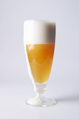 Beer with foam flowing down the edge of the glass, close-up.
