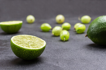 Lime halves and gooseberry berries on black background. Close up.