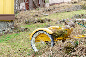 yellow garden wheelbarrow in the garden on a spring day
