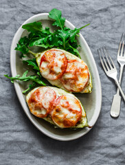 Roasted zucchini stuffed ground beef with tomatoes and mozzarella cheese on a grey background, top view