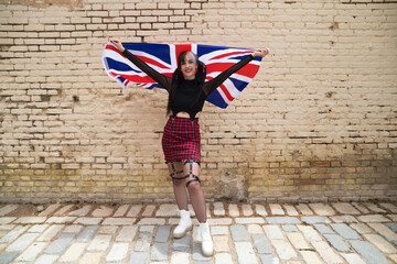 pretty young girl in punk style with the london flag on her shoulders celebrating some national event. Patriotic concept.