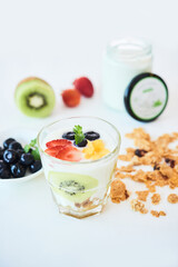 Glass with healthy low calorie dessert made of greek yogurt, berries and kiwi and decorated with mint leaves