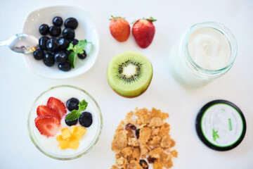 Granola with non-dairy yogurt, kiwi and fresh berries on kitchen table prepared for breakfast
