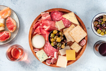 Charcuterie and cheese board with wine and olives, top shot. Sandwiches, jamon, blue cheese, glasses of rose and red wine, a flat lay. Delicious Mediterranean food