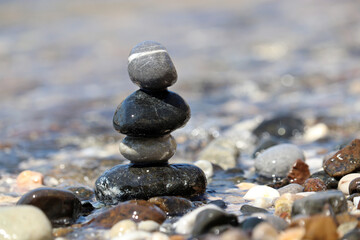 Tower of pebbles on blurred background of the sea waves. Summer vacation, balance and relax concept