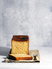 Freshly baked milk bread - blue-gray backdrop, front view with slice, portrait orientation.