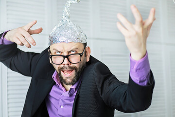 Bearded funny man in a cap of aluminum foil. Concept art phobias.Conspiracy theory. Conspiracy....