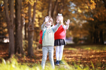 Fototapeta premium Children with briefcases for a walk in the park. School break. The beginning of the children's studies.