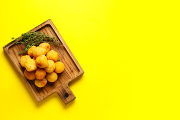 Board with fried potato balls on color background