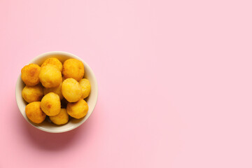 Bowl with fried potato balls on color background
