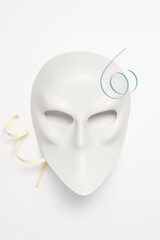 White venetian or theatrical mask with blue and yellow ribbons on a white background