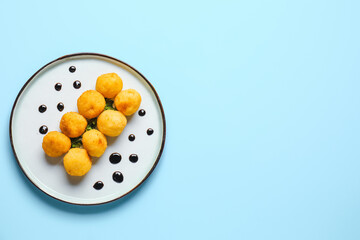 Plate with fried potato balls on color background