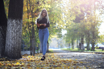 Young beautiful girl for a walk in a summer park. Leaf fall in the city park. Beginning of autumn. September.