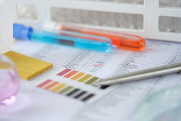 Chemical test tubes with blue and orange liquid with analysis results on table closeup