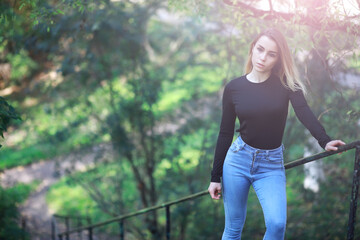 Young beautiful girl for a walk in a summer park. Leaf fall in the city park. Beginning of autumn. September.