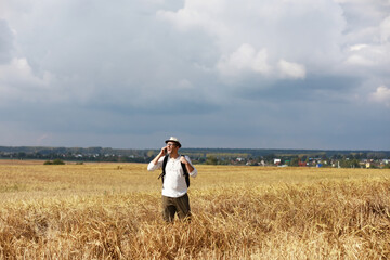 Tourist in a field of cereal plants. A man in a wheat field. Grain harvest.
