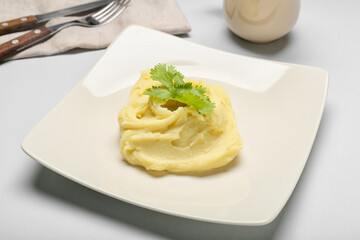 Plate with tasty mashed potatoes on light background