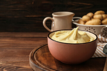 Bowl with tasty mashed potatoes on wooden background