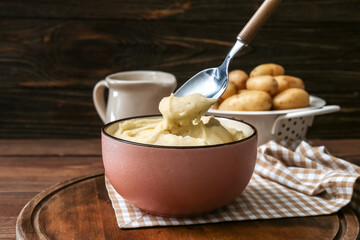 Bowl with tasty mashed potatoes on wooden background