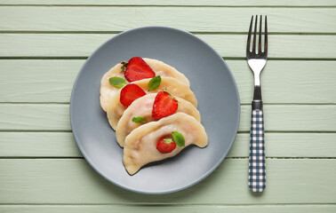 Plate with tasty strawberry dumplings on color wooden background