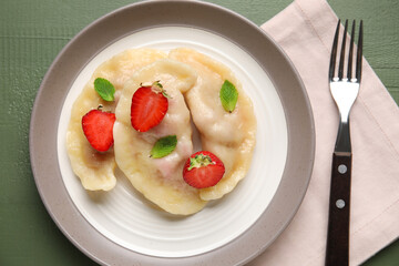 Plate with tasty strawberry dumplings on color wooden background