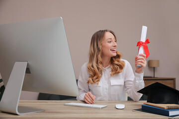 Happy student with graduation hat and diploma at workplace in office