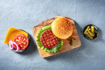 Burger ingredients. Hamburger beef patty, green salad leaf, Cheddar cheese, tomato and red onion,...