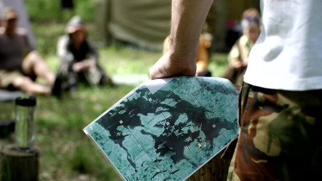 Man tells the detachment a tourist route. Close up hands of hiker tourist traveler man looking for map route. Man holds a paper map of the area in his hands. Travelling, active lifestyle