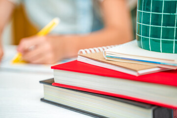Homework. A little girl does her homework at home. Textbooks in the foreground