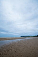 General shot at low tide of Meron beach in Cantabria, Spain, with cloudy sky, in vertical