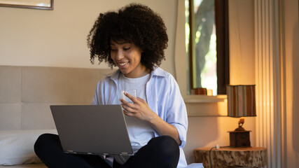 happy african woman at home using laptop, notebook,