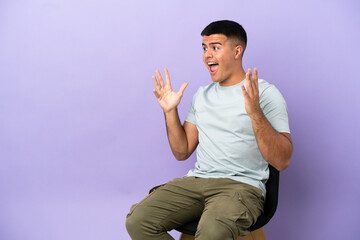 Naklejka premium Young man sitting on a chair over isolated background with surprise facial expression