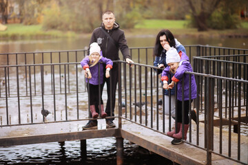 Young family on a walk in the autumn park on a sunny day. Happiness to be together.