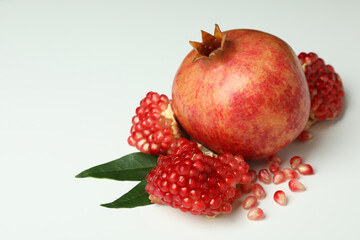 Ripe pomegranate with leaves on white background