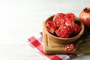 Cutting board with pomegranate on white wooden table