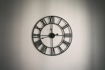 Big black colour clock hangs on white wall of kitchen room