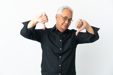 Naklejka premium Middle age Brazilian man isolated on white background showing thumb down with two hands