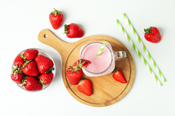 Glass jar of strawberry milkshake and ingredients on white background