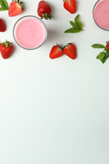 Glasses of strawberry milkshake and ingredients on white background