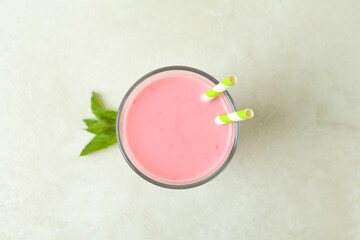 Glass of strawberry milkshake on white textured table