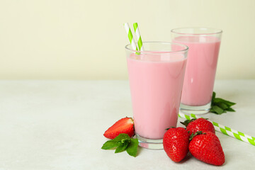 Glasses of strawberry milkshake and ingredients on white textured table