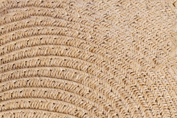 Texture background of a straw hat or bag, light sandy yellow shade close-up. Summer accessories or backgrounds.