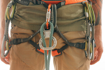 Close-up on a special 'Eight' device for belaying. Various climbing equipment hangs on the harness.