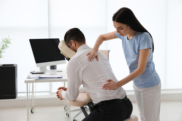 Man receiving massage in modern chair indoors