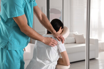 Woman receiving massage in modern chair indoors