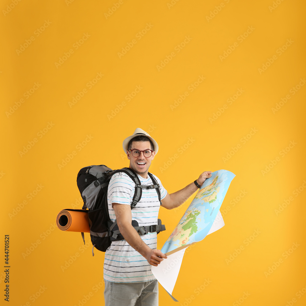 Poster Excited male tourist with travel backpack and map on yellow background