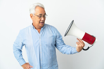 Middle age Brazilian man isolated on white background holding a megaphone with stressed expression